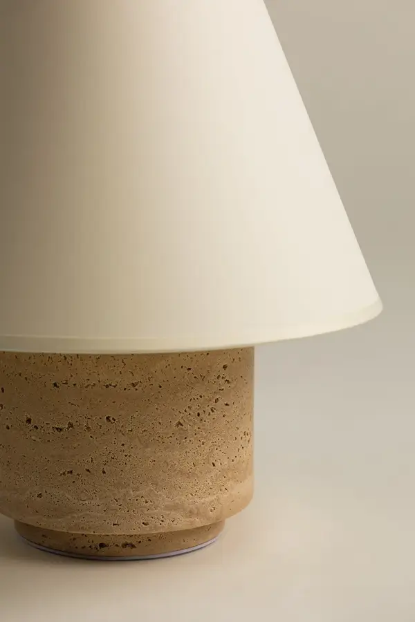 The Bronte Table Lamp combines natural travertine stone with refined brass detailing for an earthy yet sophisticated aesthetic. Its tapered paper shade creates warm ambient lighting while highlighting the stone's unique texture. - alternate view