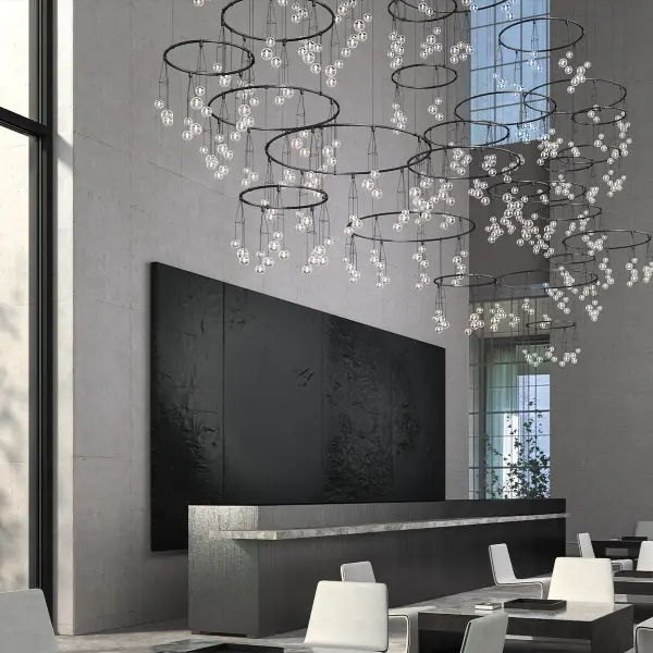 This architectural lighting system features clusters of glass bubble luminaires suspended around intersecting power bar rings of varying diameters, creating a dazzling sculptural installation that fills large volumes with dramatic presence and shimmering reflections.