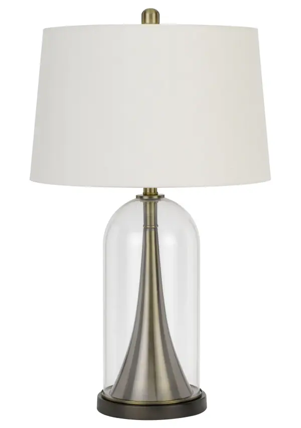 The Camargo table lamp combines a sophisticated glass body with warm antique brass accents, creating a versatile lighting solution that bridges traditional and contemporary design aesthetics at 28.5" tall.