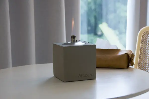 This contemporary square oil lamp combines industrial concrete aesthetics with functional safety design. The cement base provides stability while the stainless steel burner delivers 60 minutes of ambient flame lighting. - alternate view