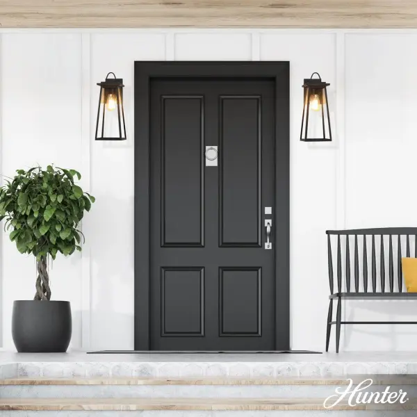 The Ivory Dusk brings timeless cottage charm to exterior spaces with its graceful 18-inch tapered silhouette. The sculpted loop detail and matte black finish create sophisticated curb appeal while the clear glass showcases vintage Edison bulbs beautifully. - alternate view