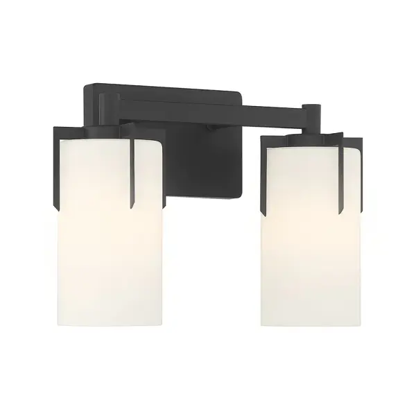 The Froselle vanity fixture elevates bathroom design with cylindrical frosted glass shades held by distinctive jewelry-style prongs. The matte black finish provides modern sophistication while delivering warm, inviting task lighting.