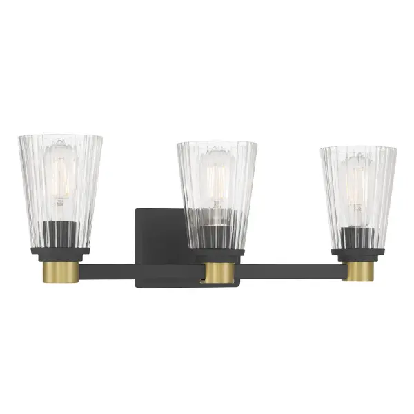 The Lustria 3-Light Vanity combines matte black and vintage brass finishes with clear ribbed glass shades for a striking retro-futuristic aesthetic. Perfect for modern bathrooms seeking industrial charm with Art Deco flair.