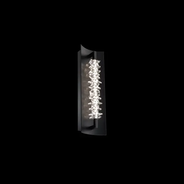 Bold and unapologetically modern, this crystal wall light pushes the boundaries of elegance with its sharp, linear design and precision craftsmanship. The faceted plates, reminiscent of jagged icebergs, are stacked in a striking formation within a curved backplate, delivering a powerful visual statement. Hidden within the crystal’s core, a line of LEDs injects a sleek glow, amplifying its raw brilliance.