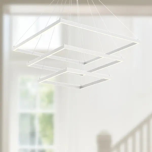 The Piazza 32" chandelier combines architectural elegance with functional lighting through its rectilinear frame and dual LED system. Downward opal diffuser provides task lighting while upward ambient LEDs create atmospheric glow. - alternate view