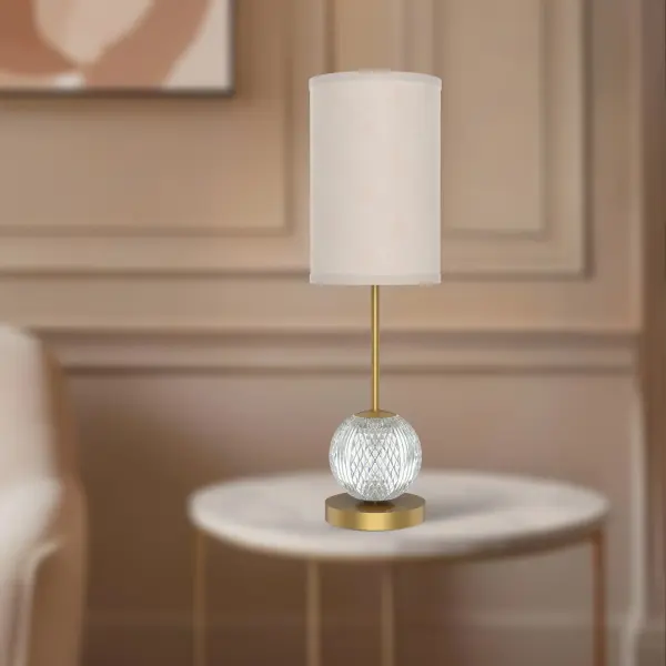 The Marni table lamp combines meticulously cut crystal spheres with a polished nickel finish and white linen shade, creating glittering beams of light. Features integrated LED with warm 3000K lighting that illuminates both from within the shade and through the crystal base for sophisticated ambiance. - alternate view