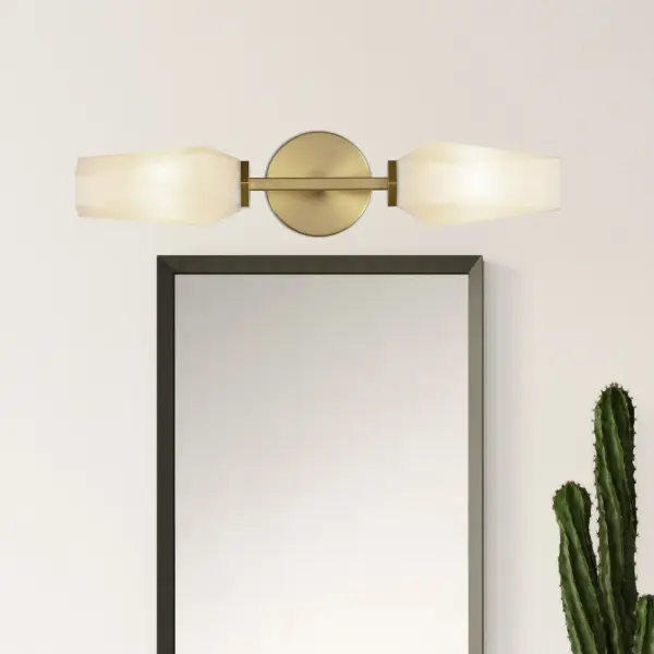 The Krysta vanity light combines clean geometric lines with faceted glass that creates stunning light patterns. Its brushed gold finish and opal glass shades deliver both sculptural beauty and practical illumination for bathrooms and beyond. - alternate view