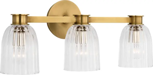 The Asalea Triple Vanity Light combines classic hand-rubbed antique brass with clear glass shades for sophisticated bathroom illumination. Its three-light configuration provides balanced lighting ideal for vanity applications. - alternate view