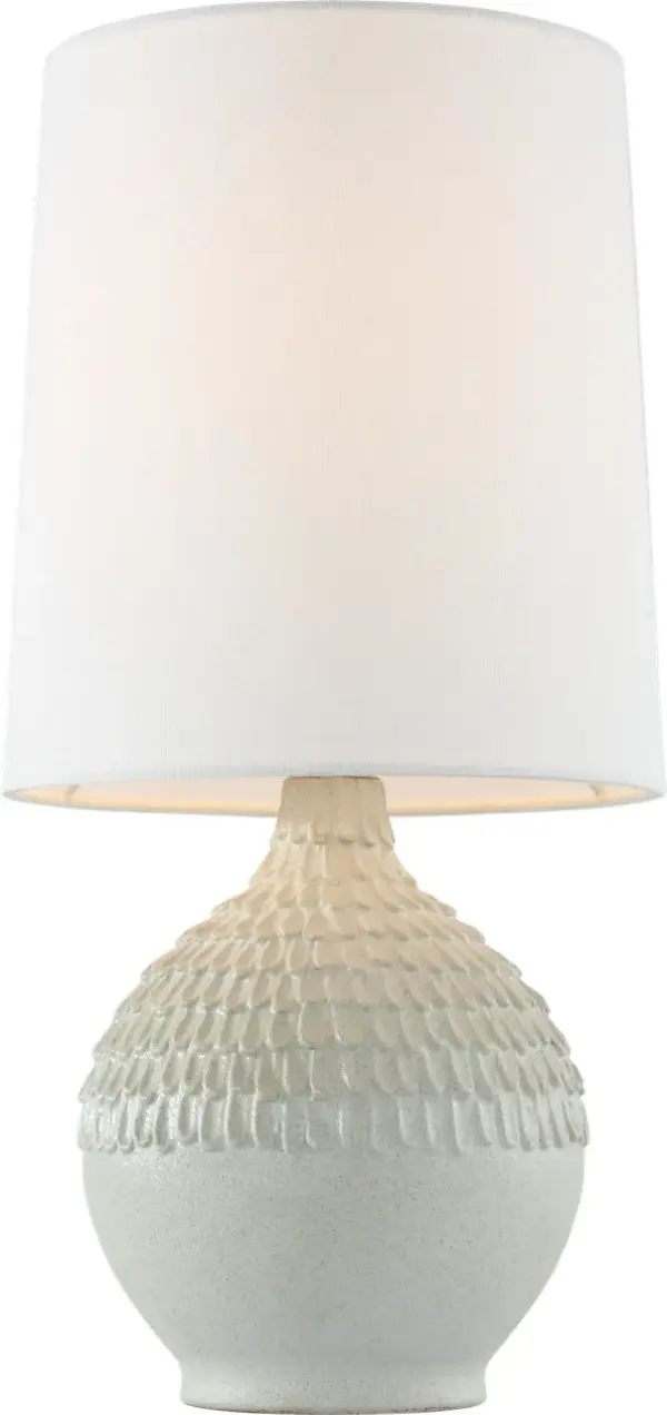 The Morava table lamp showcases hand-carved volcanic white ceramic with organic texture that brings artisanal character to any space. Its compact 17" height and neutral linen shade make it versatile for bedrooms, living areas, and offices. - alternate view
