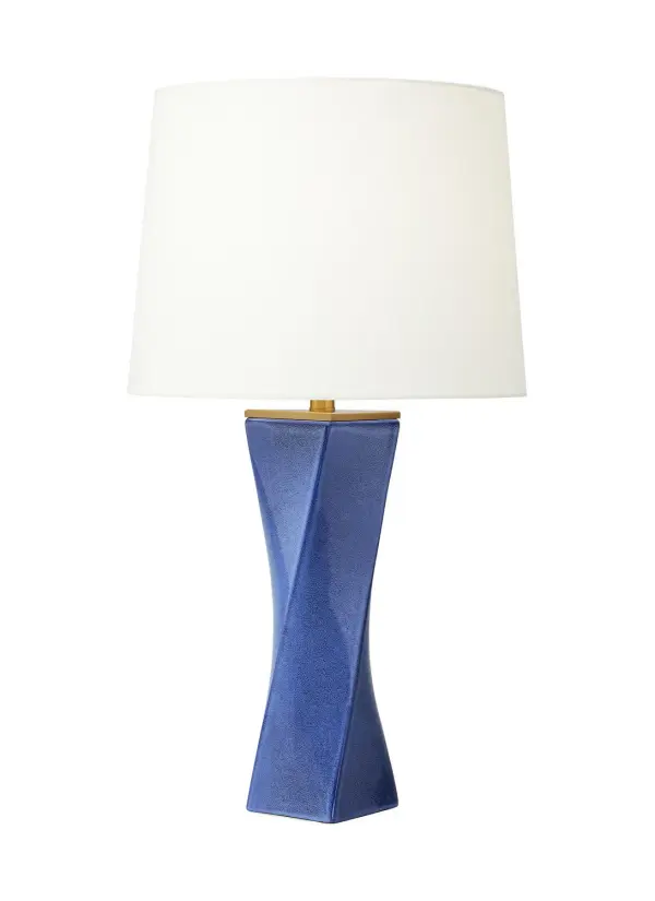 The Lagos table lamp features a striking twisted obelisk form in frosted blue glass that serves as both functional lighting and sculptural art. The substantial blown glass base paired with a crisp white linen shade creates sophisticated contrast.
