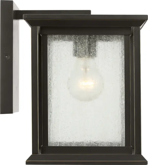 The Audley Small Wall Lantern delivers classic lantern styling in a space-conscious design. Its antique bronze finish and seeded glass create timeless appeal for entries, narrow columns, or secondary walls where full-size fixtures overwhelm.