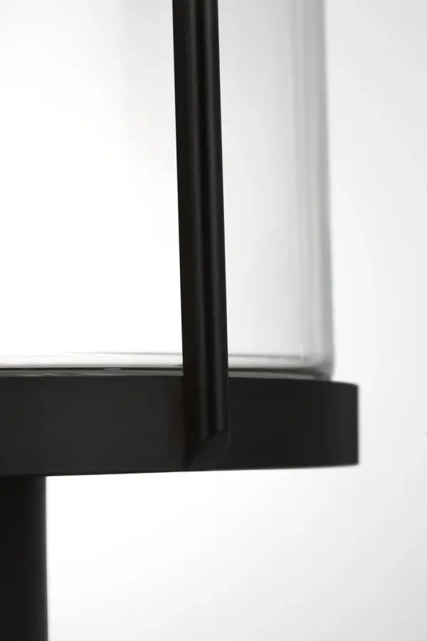 The Luning post lantern combines industrial elegance with practical outdoor performance. Its rounded metal frame and cylindrical clear glass shade deliver a subtle, welcoming glow while the textured black finish and wet-rated construction ensure long-lasting durability in any weather condition. - alternate view