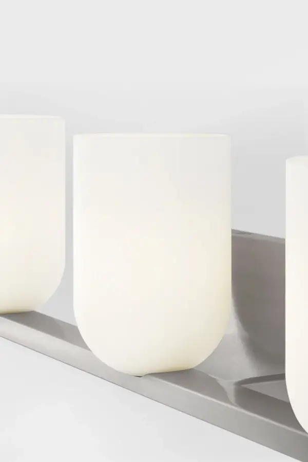 The Neblina vanity fixture combines quiet geometric design with frosted glass domes for diffused, flattering light. Perfect for primary baths and powder rooms, its brushed nickel finish and transitional style complement various décor. - alternate view