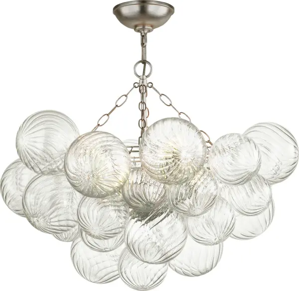 The Talia semi-flush mount by Julie Neill transforms the classic glass globe into an artisanal statement piece. Multiple swirled glass orbs in metal baskets create shimmering light effects with a playful, feminine touch.