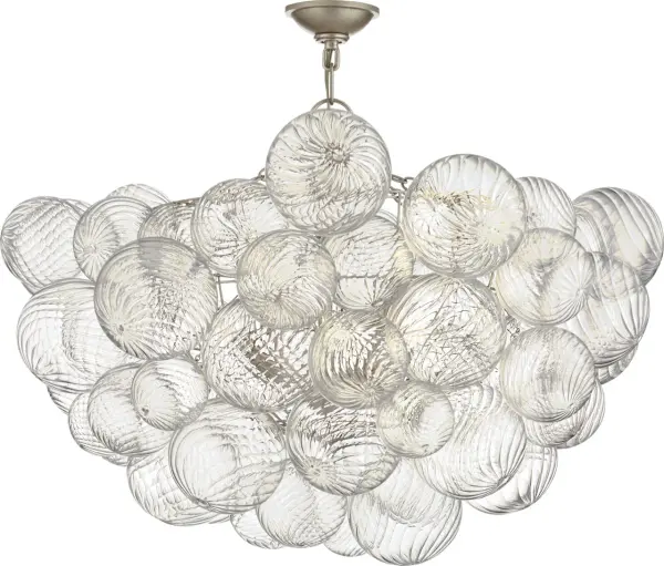 The Talia semi-flush mount by Julie Neill transforms the classic glass globe into an artisanal statement piece. Multiple swirled glass orbs in metal baskets create shimmering light effects with a playful, feminine touch.
