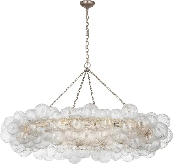 The Talia 63" Ring Chandelier by Julie Neill transforms grand spaces with its whimsical arrangement of swirled glass orbs in metal baskets. The burnished silver leaf finish adds sophisticated sparkle while the artisanal glass creates dynamic light play.