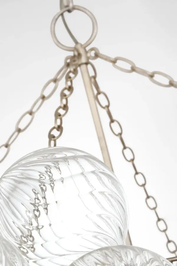 The Talia 56" chandelier by Julie Neill transforms the classic glass globe fixture with swirled artisanal glass orbs set in metal baskets. Its substantial 56-inch length makes a dramatic statement while maintaining feminine, playful charm. - alternate view