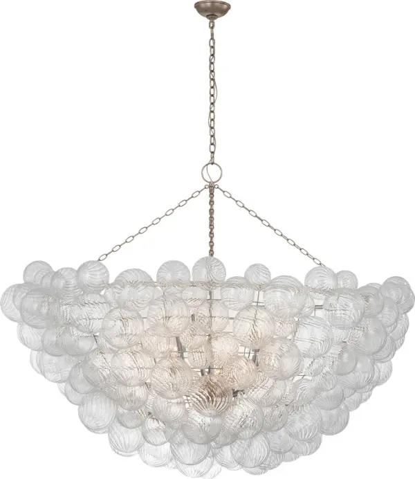 The Talia 66" chandelier by Julie Neill transforms grand spaces with its whimsical arrangement of swirled glass orbs in metal baskets. The burnished silver leaf finish adds sophisticated sparkle while the artisanal glass creates dynamic light play.