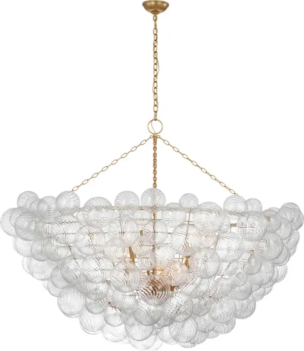 The Talia 66" chandelier by Julie Neill transforms grand spaces with multiple swirled glass orbs set in metal baskets. This oversized fixture creates dramatic visual impact through sparkling glass and bright gild finish.