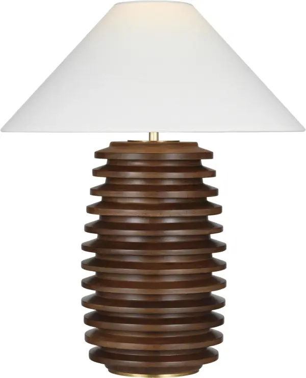 The Crenelle table lamp features a distinctive stacked wood construction in burnished birch, creating architectural interest with organic warmth. The 27" height and linen shade provide balanced proportions for versatile placement.