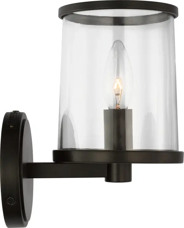 The Reynolds Small Vanity combines industrial character with refined simplicity. Its clear glass shade and sleek metal ring create sophisticated contrast, while the candelabra-style bulb adds vintage charm. Damp-rated for bathroom use.