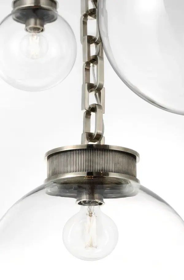 The Bellamy chandelier makes a bold architectural statement with three clear glass globes suspended on a pewter chain framework. Its transitional design bridges traditional and contemporary aesthetics, perfect for elevated dining spaces. - alternate view