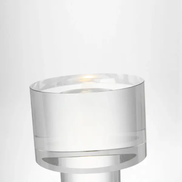 The Beryl table lamp combines translucent crystal artistry with modern brass detailing. Its cylindrical design features an etched concave base and integrated LED lighting, creating an inviting ambient glow perfect for contemporary interiors. - alternate view