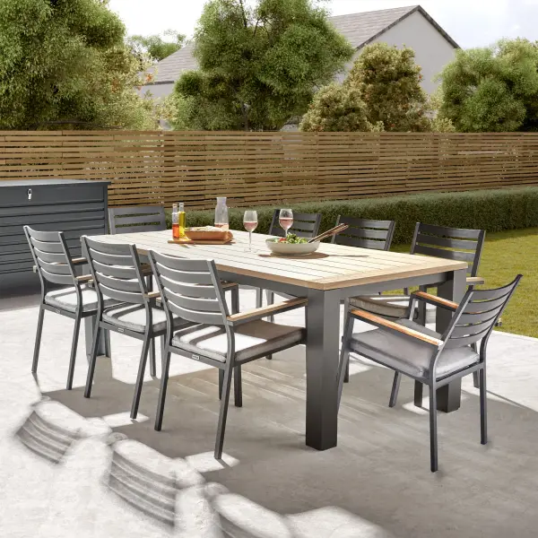 The Elba 9-Piece Dining Set combines modern rustic charm with durable functionality, making it an ideal choice for outdoor dining. The centerpiece of the set is a teak wood tabletop featuring a weathered, instant grey coating and a sleek slat-style design that adds a contemporary rustic touch. The rustproof, weatherproof charcoal aluminum frame not only complements the natural tones of the teak but also ensures lightweight durability for year-round outdoor use. This set includes eight stackable chairs with thick foam-core seat cushions, promoting proper posture and ultimate comfort. Light-Weight Charcoal Powder-Coated Aluminum Frame Weatherproof – Leave Outdoors All Year Round Solid FSC-Certified Teak Components Coordinate with the Frame Thick Foam Core Seat Cushion Promotes Proper Posture Stackable for Compact, Easy Storage Minimal Assembly Required Umbrella Hole Replaceable Foot Caps Prolong the Life of the Table and Chairs 100% Acrylic Sunbrella Cushion Fabrics for Optimal Weather Resistance Cushion Color: Spectrum Indigo Includes: 1x Table & 8x Chairs