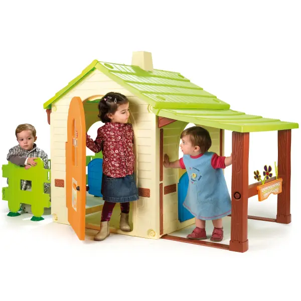 This large outdoor playhouse features country farmhouse styling with multiple doors, windows, and a covered side porch. Includes fence pieces and ground anchors for expanded play area, plus decorative flower boxes. - alternate view