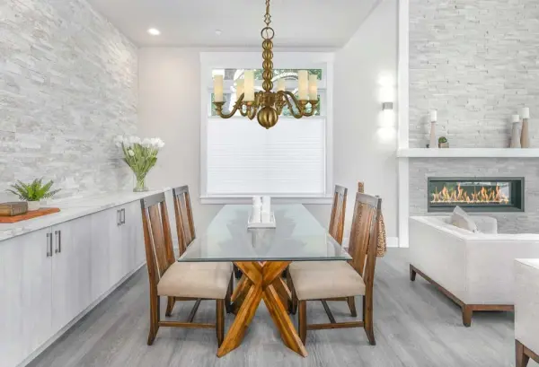 The Louisville chandelier combines classic candelabra styling with contemporary brushed brass finish and clean glass cylinders. Its 28-inch width and 6-light configuration deliver substantial illumination while maintaining refined proportions for medium dining spaces. - alternate view