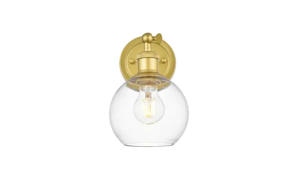 Simplicity and minimalism are the new forms of beauty when it comes to style and design. Shown in the glass shade, this wall sconce is versatile and can be placed in a bathroom,entry way, or hallway. Compatible with dimmers, so you'll have the right amount of light in any given time of the day. Available in multiple finishes. Collection: Kai Rooms: Bathroom Finish: Brass and Clear Glass: Clear Width: 6.00" Height: 10.50" Weight: 2.00 lb Extension from Wall: 10.00" Wire: 8" Black and White Canopy: 4.7"x1"x4.7" Number of Bulbs: 1 Maximum Wattage: 40.00 W Bulb Type: E26 Bulb Base: E26 Dimmable Voltage: 110.00 V Material: Iron and Glass Country of Origin: China Safety Listing: ETL Safety Rating: Damp Title 20 Title 24 Manufacturer Warranty: 1 year limited