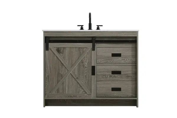 Transform your bathroom with this rustic barnyard-style vanity, designed to balance aesthetic appeal and functionality. Featuring a sliding barn door with black metal hardware and complementary handle pulls, this piece blends rugged charm with practical design. The engineered marble countertop displays unique marbling, while the porcelain undermount sink offers easy maintenance and durability. Available in Espresso, Natural Oak, and Rustic Grey finishes, this vanity suits a range of styles. It includes a deep storage drawer for larger items, a hidden shelf for towels or décor, and adjustable foot levelers for added stability on uneven floors. With pre-drilled faucet holes for easy setup, this vanity delivers style and substance to enhance your bathroom. Collection: Austin Rooms: bathroom Finish: Rustic Grey Width: 42.00" Height: 22.00" Length: 42.00" Weight: 166.00 lb Material: MDF Country of Origin: Malaysia Manufacturer Warranty: 1 year limited