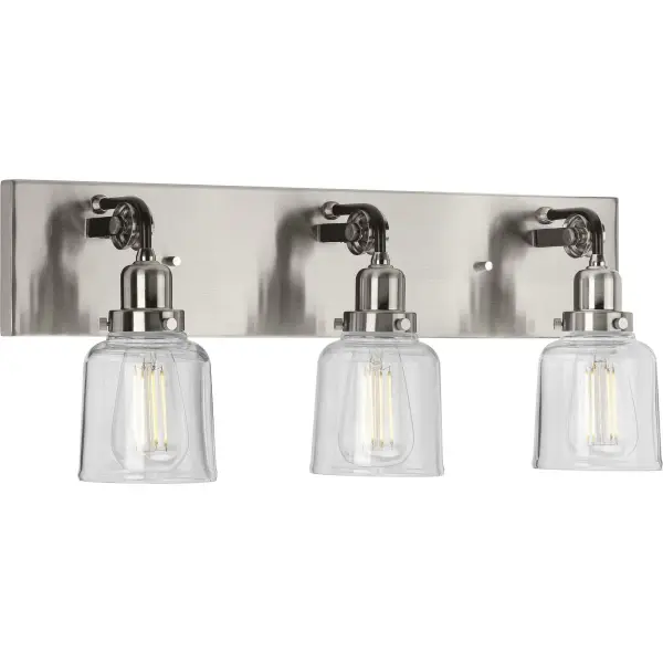 The Rushton vanity light blends urban industrial style with farmhouse warmth through clear glass cylinders and brushed nickel finish. Three lights provide ample illumination for grooming tasks while adding architectural interest.