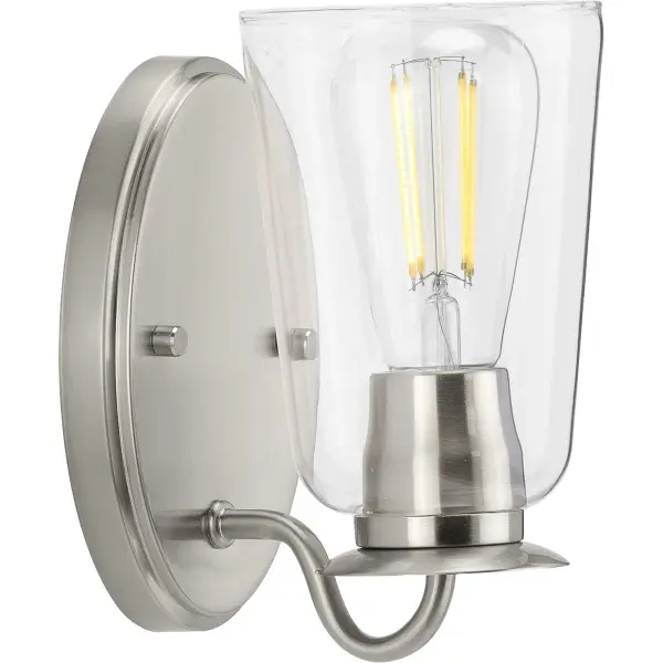 The Durrell vanity light brings fresh coastal charm to bathroom spaces with its clear glass cylinder shade and brushed nickel finish. JA8-compliant for California energy standards, this single-light fixture offers clean lines and versatile styling.