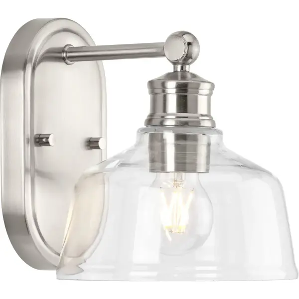 The Singleton vanity light combines industrial charm with farmhouse appeal in a compact 7.62" design. Its clear glass shade and brushed nickel finish deliver versatile style for bathrooms and powder rooms.