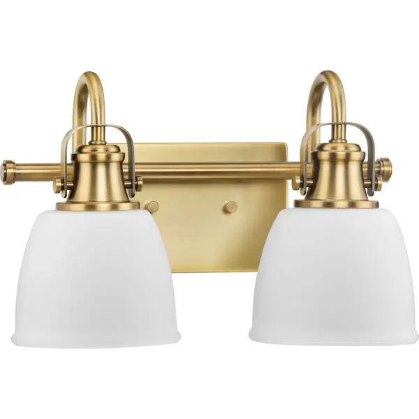 The Preston two-light vanity fixture combines vintage brass warmth with clean transitional lines, making it ideal for bathrooms seeking timeless style. Clear glass shades provide excellent task lighting while the finish adds character. - alternate view