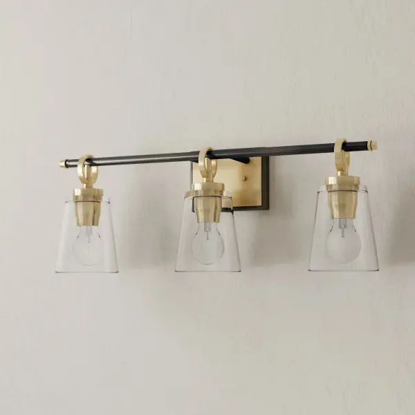 The Cassell three-light vanity fixture blends transitional elegance with industrial charm. Its brushed nickel finish and clear glass shades provide excellent task lighting for bathrooms while adding sophisticated style.