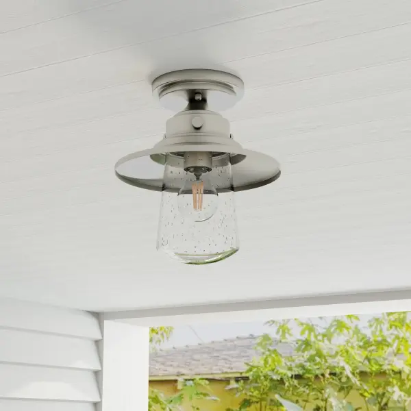 The Tremont ceiling light combines farmhouse warmth with industrial edge through its stainless steel finish and clear seeded glass shade. JA8 and Title 22 compliant, it's ideal for covered outdoor spaces and transitional interiors.