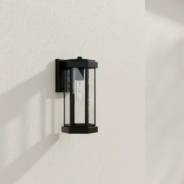 The Ramsey Small Wall Lantern blends transitional design with modern farmhouse elements, featuring a clean black finish and clear glass panels. JA8 compliant for California energy standards, this compact fixture delivers style and efficiency for residential outdoor spaces.