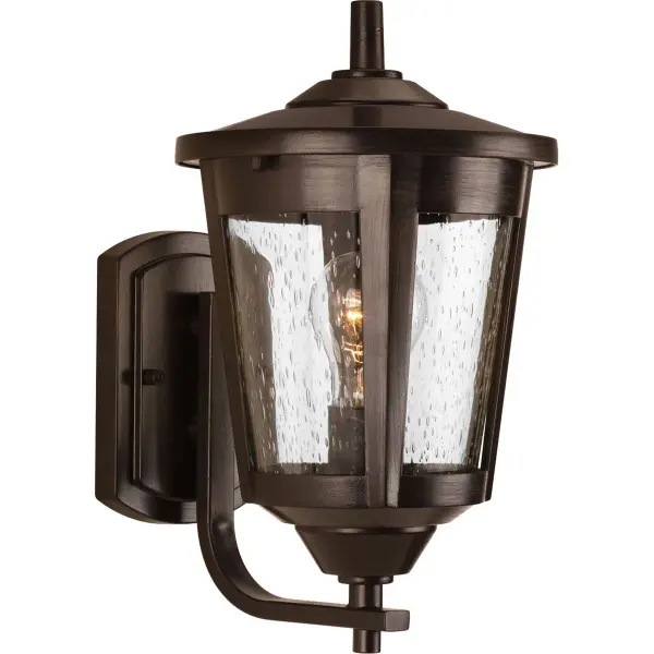 The East Haven wall lantern combines traditional lantern styling with transitional elegance. Its antique bronze finish and clear glass panels provide warm, welcoming illumination for entryways and outdoor spaces.