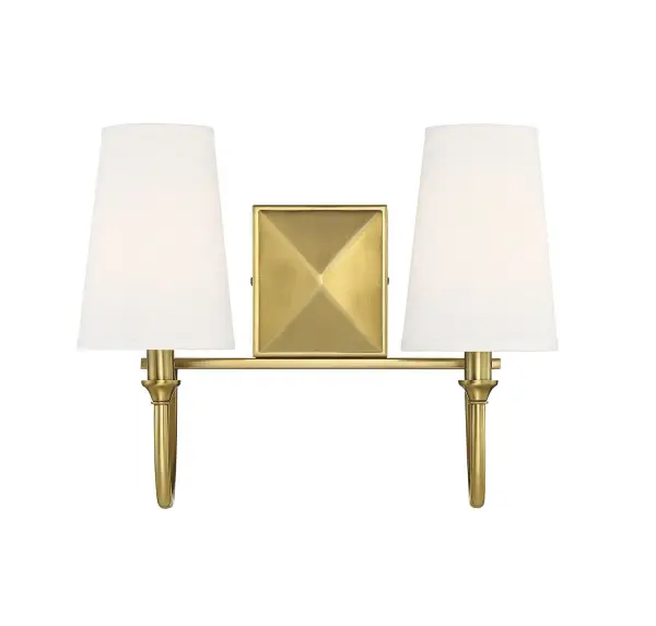 The Cameron bath bar delivers timeless sophistication with its gracefully curved arms and warm brass finish. White fabric shades provide flattering, diffused light perfect for grooming tasks while the faceted backplate adds architectural interest.