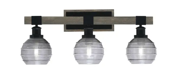 The Tacoma 3-Light Bath Bar blends industrial matte black with distressed wood-look metal for a rustic-modern aesthetic. Smoke ribbed glass shades provide soft, diffused lighting ideal for bathroom vanities.
