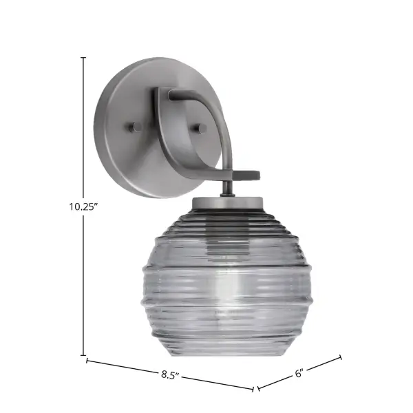 The Cavella Wall Sconce combines industrial charm with transitional elegance. Its compact 6-inch smoke ribbed glass shade and graphite finish make it ideal for bathrooms, hallways, and accent lighting. - alternate view