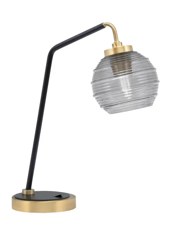 This striking desk lamp combines matte black and new age brass finishes with a 6" smoke ribbed glass shade, creating a perfect blend of industrial style and modern elegance for any workspace or bedroom.