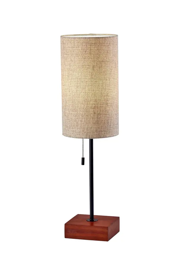The Trudy table lamp combines modern design with warm materials, featuring a cube-shaped walnut base, sleek black stem, and tall drum shade in beige and brown textured fabric. At 26.75" tall, it's perfectly sized for nightstands and desks.