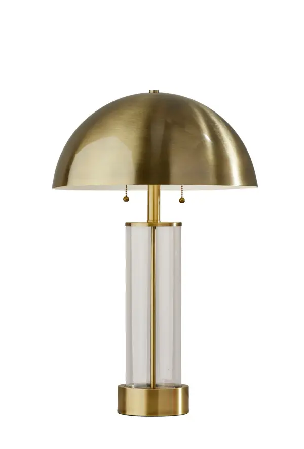 The Troy table lamp combines industrial elegance with mid-century modern design through its unique clear glass pillar and antique brass dome shade. At 25" tall with dual independent switches, it offers both style and functionality.