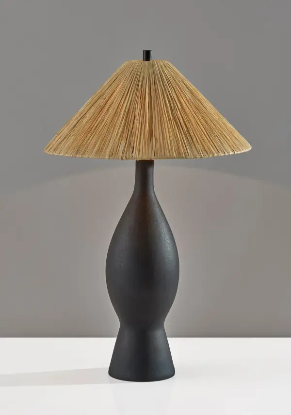 The Maren Table Lamp combines a striking hourglass-shaped black ceramic base with an organic raffia shade for a perfect blend of modern sophistication and rustic charm. At 28 inches tall, it provides substantial presence and warm ambient lighting.