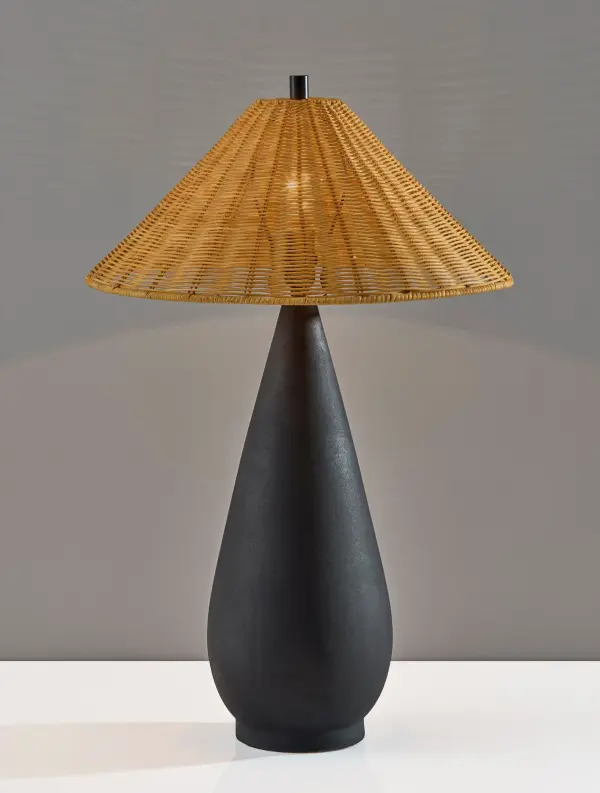 The Lorelei Table Lamp combines a striking teardrop-shaped black ceramic base with a warm brown rattan shade, creating an inviting blend of natural texture and contemporary style perfect for modern and coastal-inspired spaces.