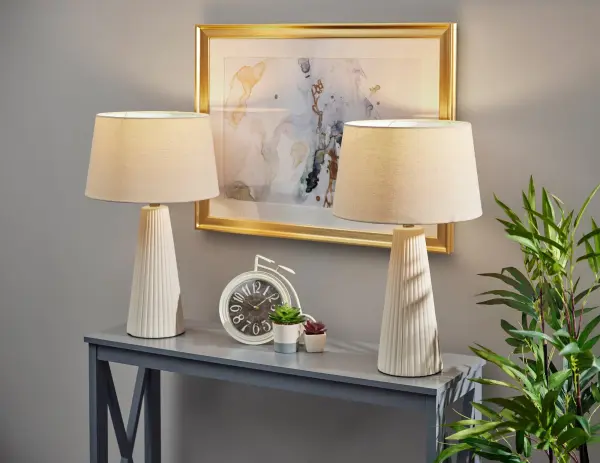 The Lana table lamp set combines modern ceramic craftsmanship with transitional style through its distinctive vertical ribbed texture. The off-white base paired with oatmeal linen drum shades creates a sophisticated neutral palette that complements diverse interiors. - alternate view