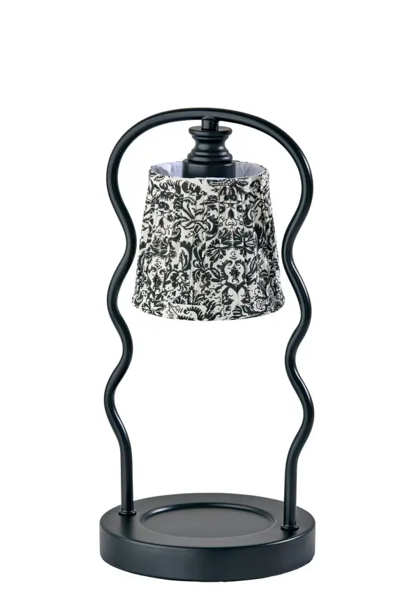 Charming, sculptural, and just a little bit edgy—the Twirl Candlewarmer Lamp in black brings a modern twist to vintage floral. Two black, wave-like metal poles swirl upward to hold a pleated black and white floral shade, creating a silhouette that's both whimsical and sophisticated. Designed to warm your favorite candles without an open flame, the built-in 50W halogen bulb releases rich fragrance safely and evenly. With a full-range dimmer and convenient timer switch, Twirl gives you total control over both brightness and burn time—no matches required. It's the ideal blend of function and flair for moody evenings, coffee table moments, or cozy bedside glow. Collection: Twirl Finish: Black Glass: White/Black Printed Fabric Width: 6.50" Height: 13.50" Length: 6.50" Weight: 3.35 lb Extension from Wall: 6.50" Wire: 60" Black Cord Bulbs Included Maximum Wattage: 50.00 W Bulb Base: GU10 Light Source: Halogen Material: Metal:60%, Fabric:30%, Electrical parts:10% Country of Origin: Cambodia Safety Listing: ETL Switch: In-Line Timer Switch Connection: Plug-in